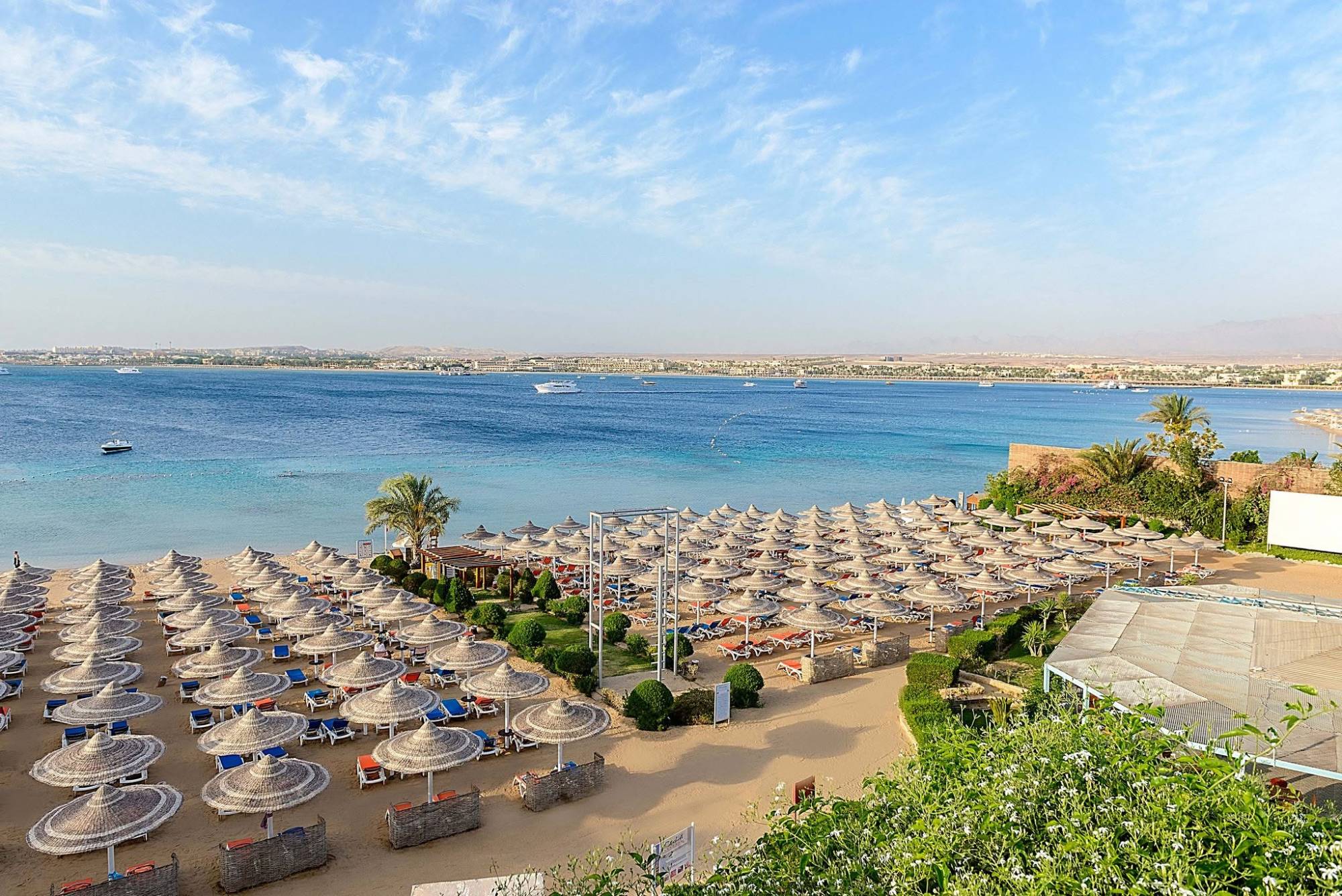 The Prima Life Makadi beach with straw parasols and the Red Sea